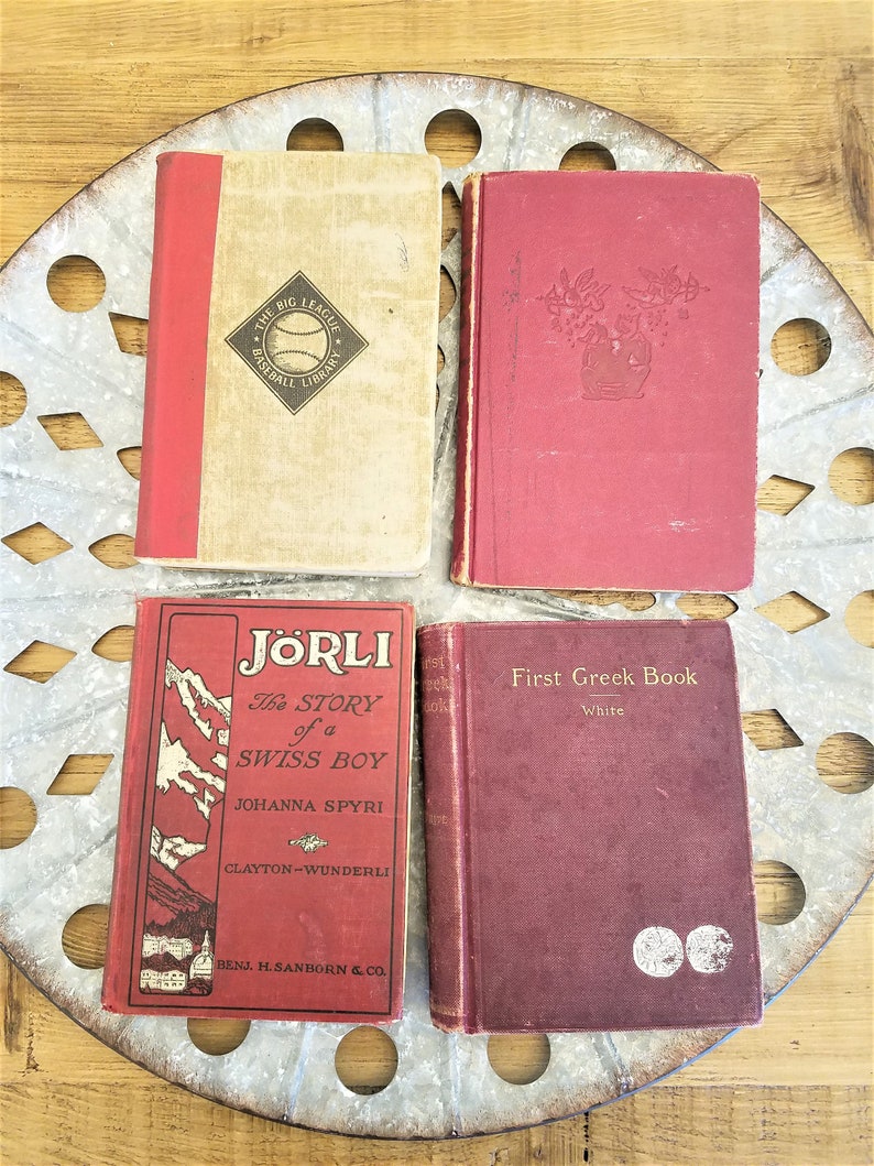 May include: Four vintage hardcover books with red covers. The books are titled "The Big League Baseball Library", "J&ouml;rli The Story of a Swiss Boy", "First Greek Book", and "First Greek Book".