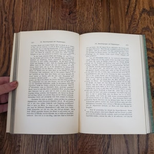 Pu&ograve; includere: Un libro aperto con una copertina verde. Le pagine sono piene di testo in tedesco. Il libro &egrave; intitolato "Berichtigungen und Erg&auml;nzungen".