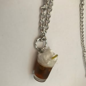 May include: A silver chain necklace with a charm of a glass of iced coffee with whipped cream and a straw.
