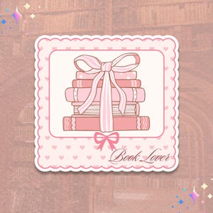 May include: A pink sticker with a stack of books tied with a pink ribbon. The sticker has a scalloped edge and a heart pattern. The words "Book Lover" are written in cursive.