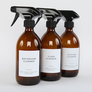 May include: Three amber glass spray bottles with black spray tops and white labels. The labels read "Bathroom Cleaner", "Glass Cleaner", and "Kitchen Cleaner".