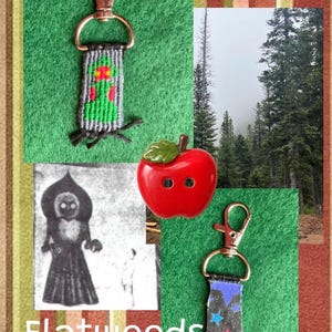 Puede incluir: Dos llaveros tejidos con cierres de mosquet&oacute;n de metal, uno con una figura alien&iacute;gena verde y el otro con un fondo negro con estrellas azules y rosas. Un bot&oacute;n rojo brillante en forma de manzana con una hoja verde y el texto Flatwoods Monster.