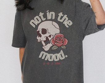 Może przedstawiać: Szary t-shirt z przetartym wyglądem przedstawia grafikę czaszki z czerwoną różą i tekstem "not in the mood."