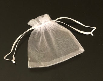 May include: A white sheer drawstring bag made of delicate fabric. The bag is empty and has a white drawstring.