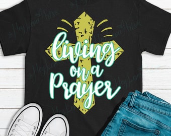 May include: A black t-shirt with a yellow cross and the text "Living on a Prayer" in white and green lettering.
