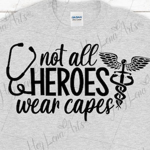 May include: Light gray t-shirt with the text "not all HEROES wear capes" in black. A black stethoscope graphic is on the left, and a medical symbol is on the right.