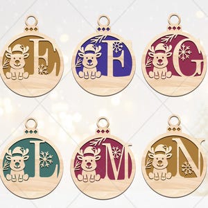 May include: Wooden Christmas ornaments with a reindeer design and letters E, F, G, L, M, and N. Each ornament features a different color for the letter and snowflake accents. The ornaments are round with a small hole at the top for hanging.