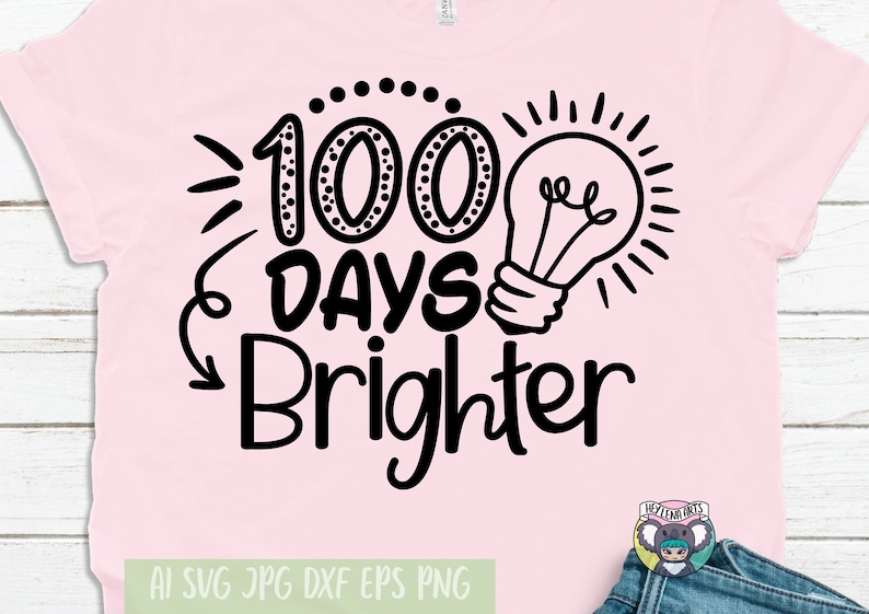 Puede incluir: Camiseta rosa con texto negro que dice "100 Days Brighter" con un gr&aacute;fico de bombilla. El texto est&aacute; escrito a mano.