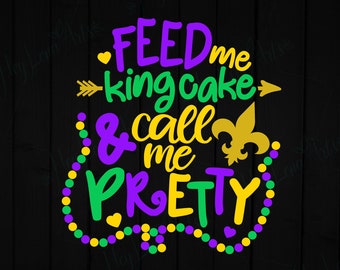 May include: Purple, green, and yellow text on a black background reads "Feed me king cake & call me pretty". The text is surrounded by a string of green, purple, and gold beads.