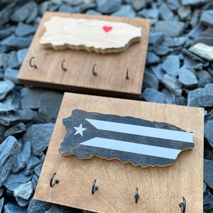 K&ouml;nnte beinhalten: Schl&uuml;sselhalter aus Holz in Form der Insel Puerto Rico mit einem roten Herzen oben und vier Haken unten. Der Schl&uuml;sselhalter ist aus hellbraunem Holz gefertigt und hat eine nat&uuml;rliche Holzoptik.