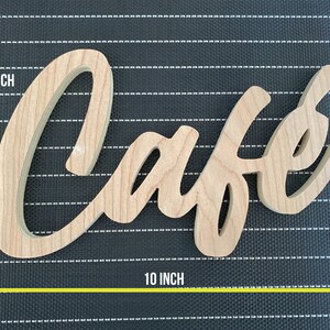 May include: Wooden sign with the word "Cafe" in a cursive font. The sign is 10 inches wide and 6 inches tall.