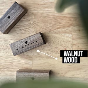 Puede incluir: Tres peque&ntilde;as cajas de madera con un dise&ntilde;o de coraz&oacute;n y la palabra "Recuerdos" grabada en una de las cajas. Las cajas son de madera de nogal y est&aacute;n sobre una superficie de madera clara.