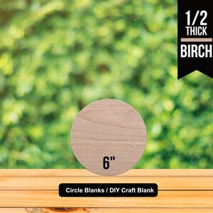 May include: A 6 inch diameter, 1/2 inch thick unfinished birch wood circle blank. The blank is shown on a wooden surface with a blurred green background. Circle Blanks / DIY Craft Blank.