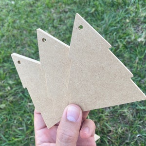 May include: Three unfinished wooden Christmas tree decorations with a hole at the top for hanging.