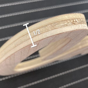 May include: Close-up of the edge of a wooden cutout, showing the layers of plywood. The cutout is 1/2 inch thick.