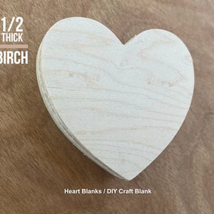 May include: A plain, unfinished, heart-shaped wooden craft blank made from birch wood. It is 1/2 inch thick. The blank is on a brown wooden surface. Heart Blanks / DIY Craft Blank
