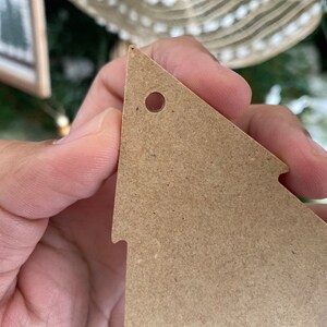 May include: A brown cardboard Christmas tree bauble with a hole punched in the top for hanging.