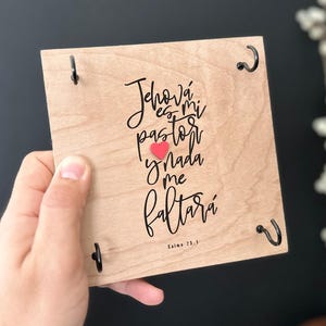 May include: Wooden sign with black metal hangers and a red heart. The sign reads "Jehov&aacute; es mi pastor nada me faltar&aacute;" with the text "Salmo 23:1" at the bottom.