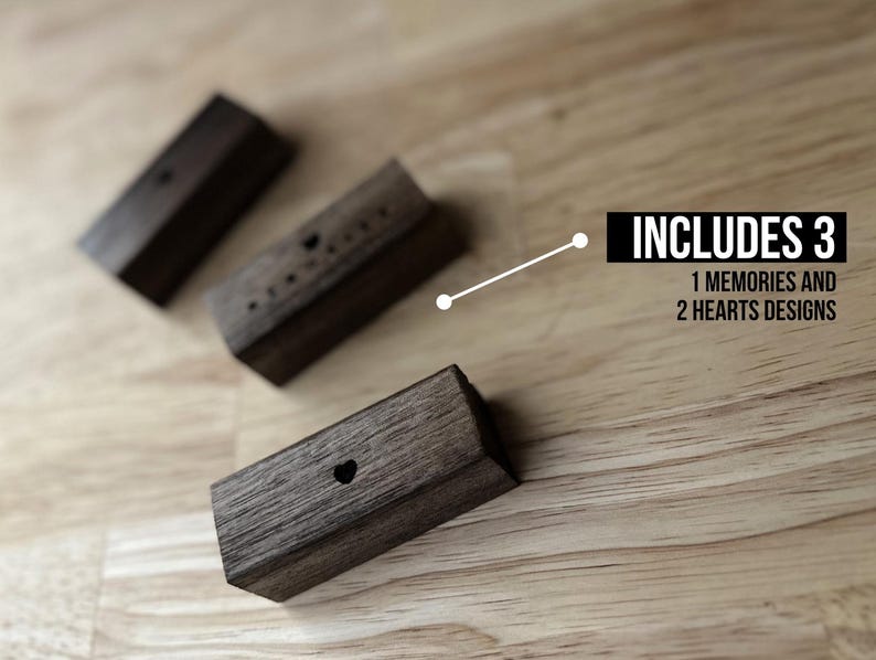Puede incluir: Tres bloques de madera con diferentes dise&ntilde;os. Un bloque tiene la palabra "Memories" tallada en &eacute;l, y los otros dos bloques tienen formas de coraz&oacute;n talladas en ellos. El texto "INCLUDES 3" es visible sobre los bloques, con el texto "1 MEMORIES AND 2 HEARTS DESIGNS" debajo.