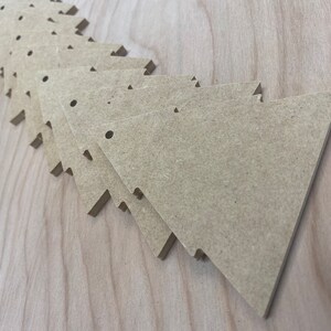 May include: A stack of unfinished, light brown wooden triangle shapes with rounded corners. Each triangle has two small holes drilled near the top.