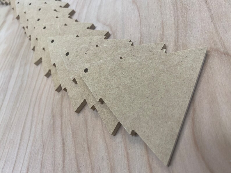 May include: A stack of unfinished, light brown wooden triangle shapes with rounded corners. Each triangle has two small holes drilled near the top.