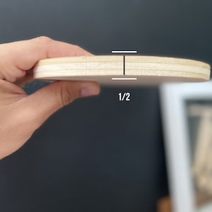 May include: A close-up of a round wooden plaque, showing the thickness of the wood, which is 1/2 inch.
