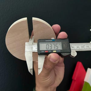 Puede incluir: Un primer plano de un calibre digital que mide un c&iacute;rculo de madera con un di&aacute;metro de 0,375 pulgadas. El c&iacute;rculo est&aacute; dividido en dos y el calibre est&aacute; midiendo el ancho de la divisi&oacute;n.