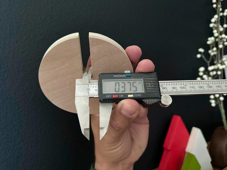Puede incluir: Un primer plano de un calibre digital que mide un c&iacute;rculo de madera con un di&aacute;metro de 0,375 pulgadas. El c&iacute;rculo est&aacute; dividido en dos y el calibre est&aacute; midiendo el ancho de la divisi&oacute;n.