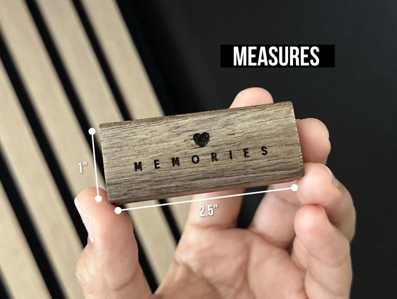 Puede incluir: Un peque&ntilde;o bloque de madera con la palabra "MEMORIES" grabada en &eacute;l. El bloque mide 6,35 cm de largo y 2,54 cm de ancho.