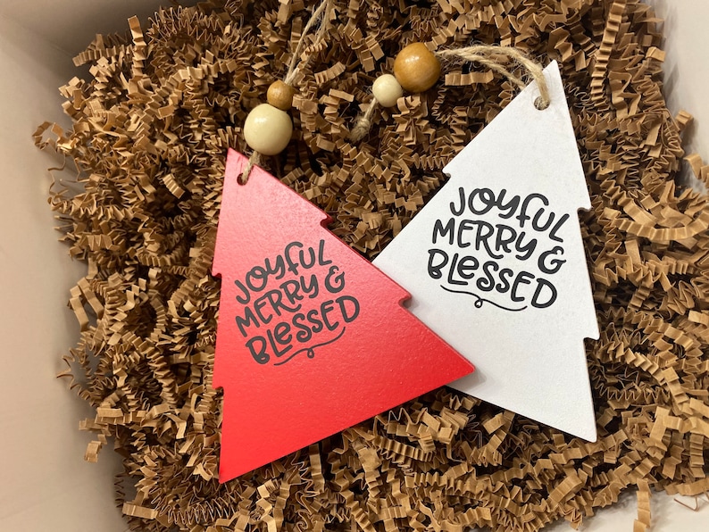 May include: Two wooden Christmas tree decorations, one red and one white, both with the text "Joyful Merry & Blessed".