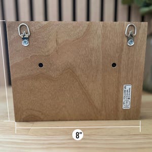 K&ouml;nnte beinhalten: Ein Holzschild mit zwei Metall-Aufh&auml;nghaken auf der R&uuml;ckseite. Das Schild ist 20,3 cm breit und 15,2 cm hoch. Das Schild hat einen kleinen Aufkleber auf der rechten unteren Ecke, auf dem "Follow Us @fireandfloral" steht.