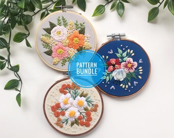 Könnte beinhalten: Drei Stickmuster in Stickrahmen mit floralen Designs. Das erste Muster ist ein Strauß aus rosa, orangefarbenen und gelben Blumen auf hellgrauem Hintergrund. Das zweite Muster ist ein Strauß aus rosa und roten Blumen auf dunkelblauem Hintergrund. Das dritte Muster ist ein Strauß aus weißen Blumen und orangefarbenen Beeren auf cremefarbenem Hintergrund. Der Text "PATTERN BUNDLE" ist in der Mitte des Bildes sichtbar.
