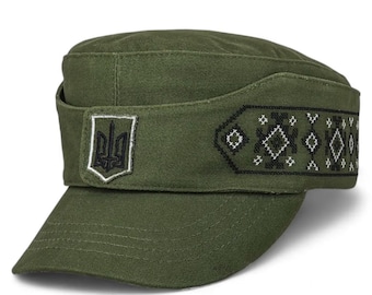 May include: Olive green cap with a structured crown and a short brim. The cap features a band with a geometric pattern in black and white. A white and black emblem is on the front.