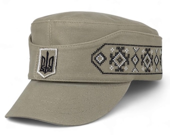 May include: A khaki military-style cap featuring a flat top and a stiff brim. The front displays a white and black embroidered trident emblem, while the side band is decorated with a black and white geometric cross-stitch pattern.