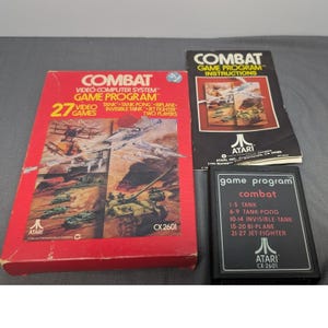 Può includere: Un set di videogiochi Atari Combat che include una scatola di cartone rossa con illustrazioni, un manuale di istruzioni nero e una cartuccia di gioco nera. La scatola riporta il testo Combat Video Computer System Game Program e 27 giochi.
