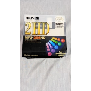 Puede incluir: Un disquete micro Maxell 2HD de 3,5 pulgadas. El embalaje presenta el texto "2HD" en letras doradas grandes, junto con el número de modelo MF2-256HD. El embalaje también incluye gráficos coloridos y texto japonés.