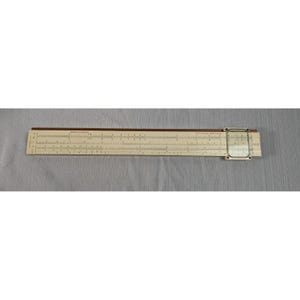 May include: A vintage slide rule with a cream-colored body and dark brown trim. The rule features multiple scales and markings for calculations, with a clear plastic cursor. The slide rule is a classic tool for mathematical computations.