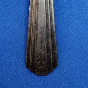 May include: A silver teaspoon with a simple design and a floral pattern on the handle.