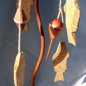 May include: A rustic metal candle holder with a wooden base and a rope trim. It features a decorative design of hanging wooden fish and a red and white fishing bobber.