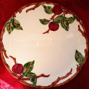 May include: A white ceramic serving platter with a brown twig design and red apples with green leaves.