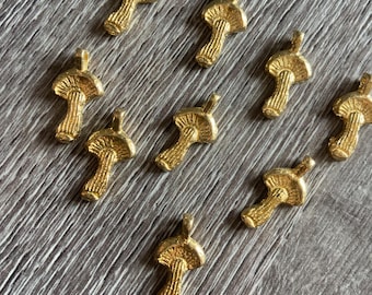Könnte beinhalten: Zehn goldfarbene Pilz-Anhänger. Die Anhänger sind alle gleich groß und haben die gleiche Form und ein detailliertes Design.