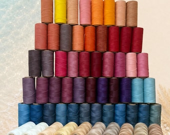 Op de afbeelding: Een verzameling Linhasita 0,75 mm garenklosjes gerangschikt in een piramidevorm. De klosjes hebben een breed kleurenspectrum, waaronder tinten geel, oranje, rood, roze, paars, blauw, bruin en wit, met de tekst Linhasita 0,75 mm bovenaan.