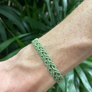 Pode incluir: Um bracelete de amizade trançado verde com um padrão tecido.