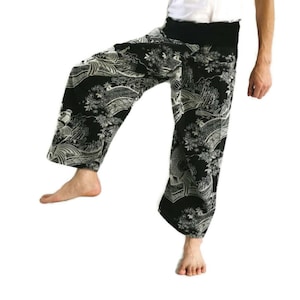 May include: Black trousers with a white floral and wave pattern. The trousers have an elastic waistband and a loose fit.