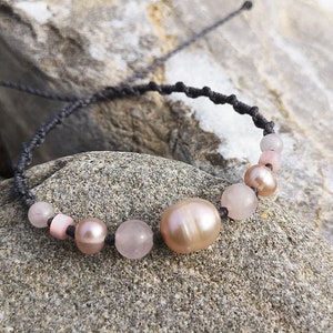 Può includere: Una collana delicata con perline rosa e bianche infilate su un cordoncino nero. Le perline sono un mix di perle lisce e rotonde e pietre sfaccettate.