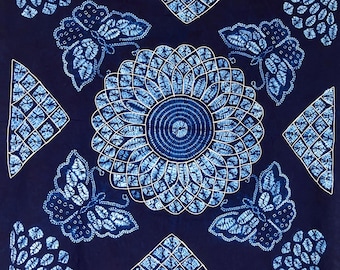 Könnte beinhalten: Ein quadratisches Textil mit tiefblauem Hintergrund und einem zentralen kreisförmigen Mandalamuster in Weiß und Hellblau. Vier Schmetterlinge sind um die Mitte angeordnet, flankiert von vier dreieckigen geometrischen Motiven und Eckakzenten.