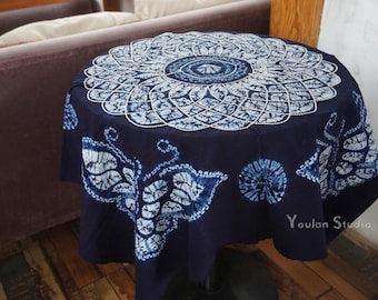 Könnte beinhalten: Ein runder marineblauer Tischläufer mit einem weiß-blauen Mandala-Design in der Mitte. Der Tischläufer hat Blatt- und Kreis-Muster in Weiß und Blau an den Rändern. Der Tischläufer liegt auf einem kleinen runden Tisch.