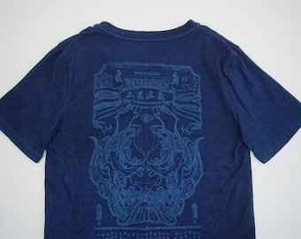 Könnte beinhalten: Ein dunkelblaues T-Shirt mit kurzen Ärmeln und einem großen, detaillierten Grafikdruck auf der Rückseite. Das Design zeigt stilisierte Linienzeichnungen eines maskenartigen Gesichts, dekorative Banner und chinesische Schriftzeichen in Hellblau.