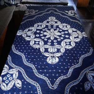 May include: A blue and white patterned tablecloth with a geometric design. The tablecloth is made of a soft, textured fabric and features a repeating pattern of leaves and flowers.
