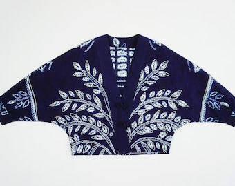 Könnte beinhalten: Dunkelblaue Jacke im Kimono-Stil mit weißem Blättermuster. Die Jacke hat einen V-Ausschnitt und weite Ärmel. Das Blattmuster ist symmetrisch, wobei die Blätter von der Mitte ausgehen. Die Jacke ist aus einem weichen Stoff gefertigt.